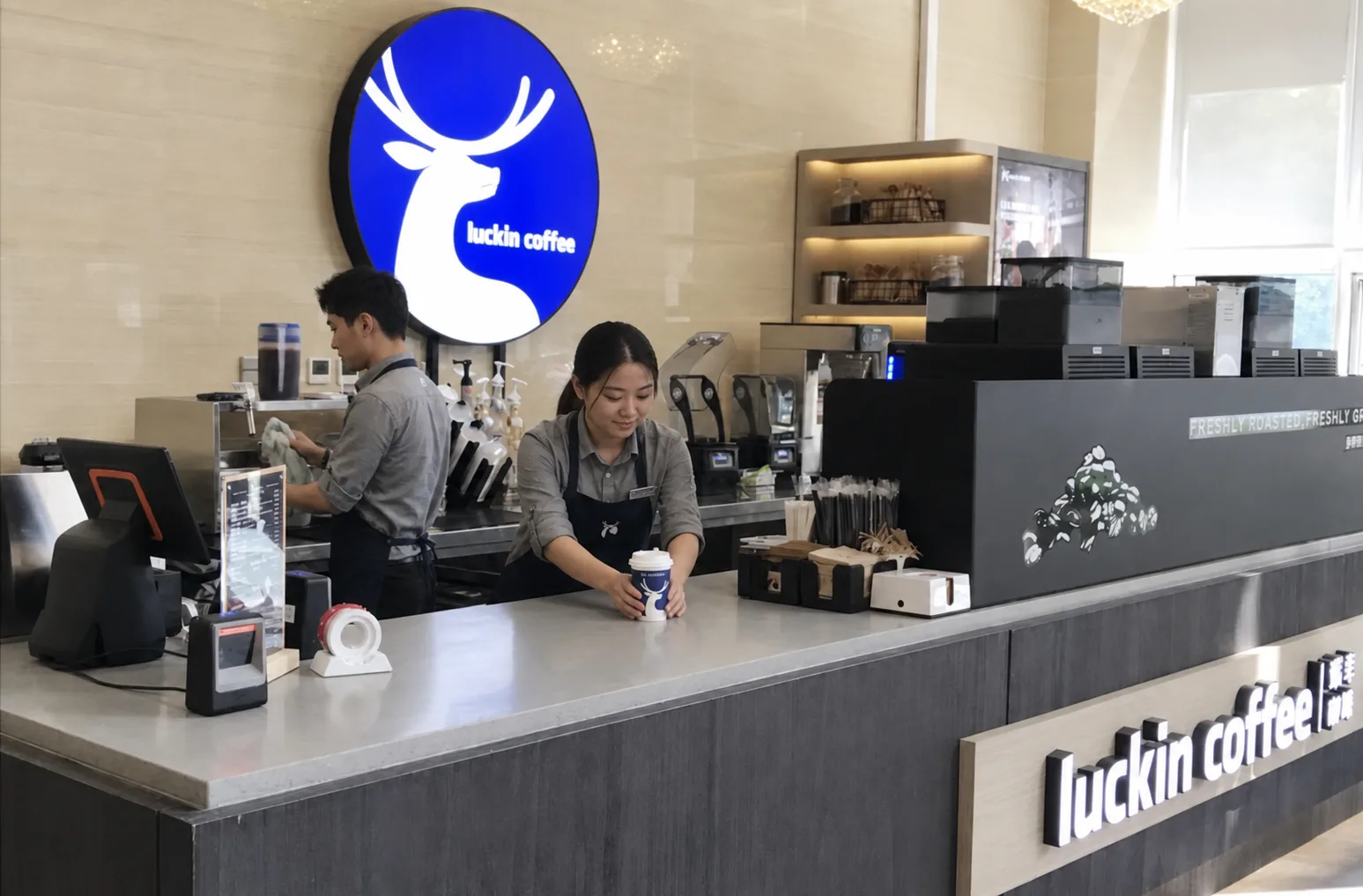 Two employees preparing and placing an order inside a Luckin Coffee store