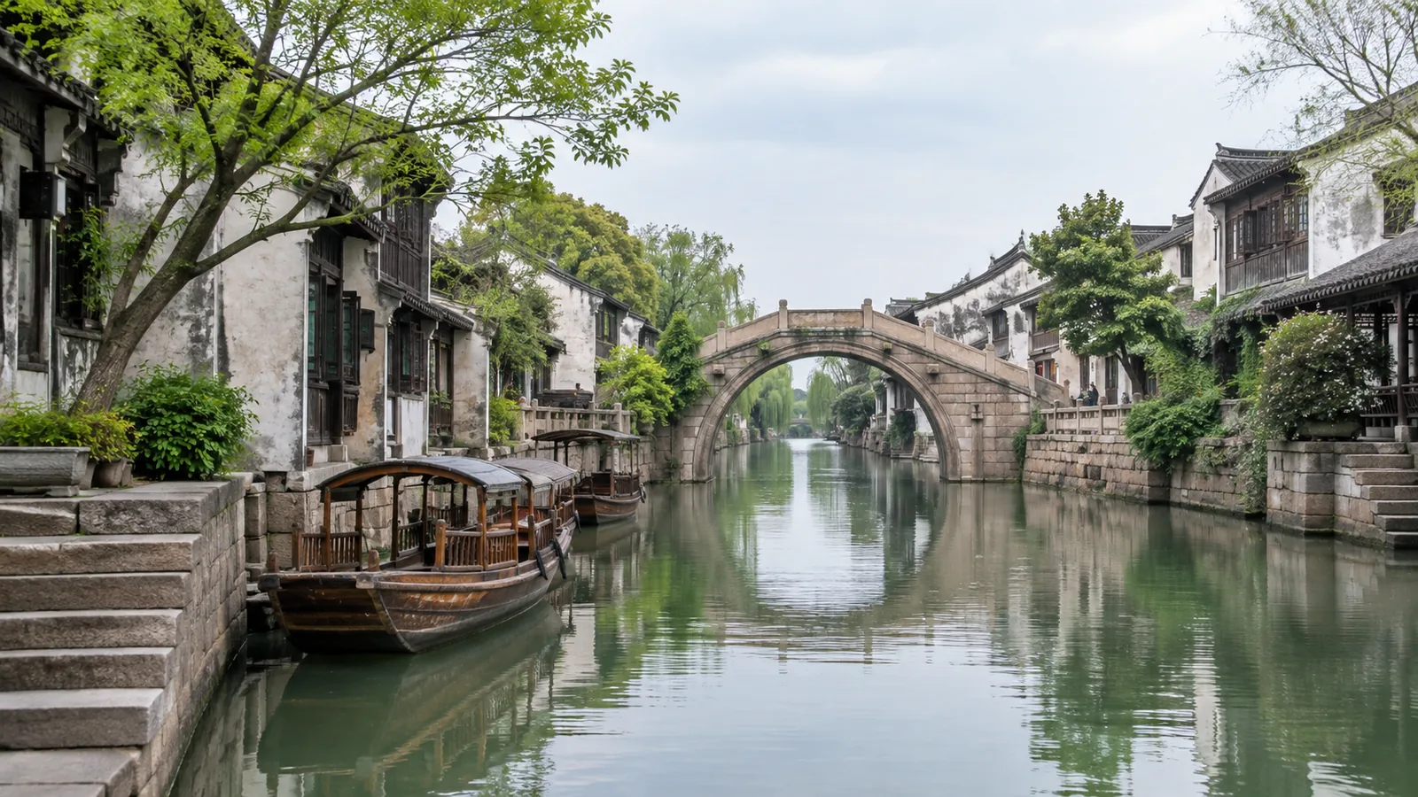 A quiet Jiangnan canal with whitewashed houses, stone bridge and moored wooden boats